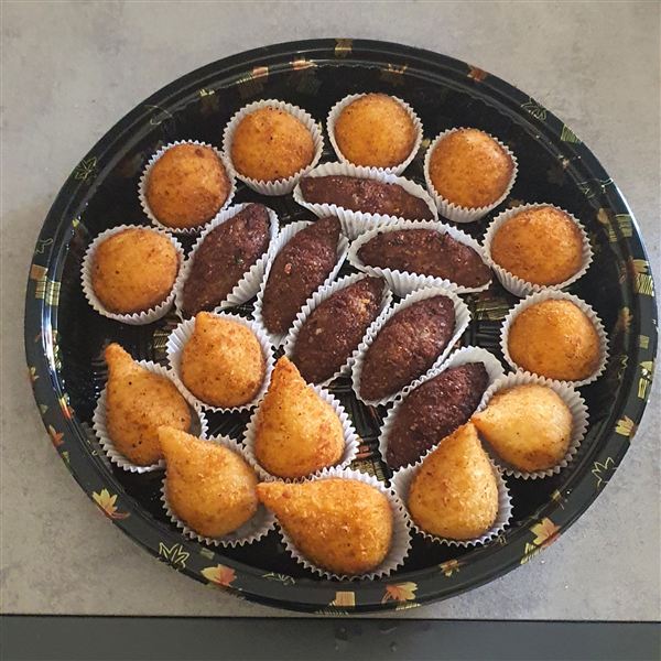 Un vassoio di salgados brasiliani dorati, con coxinhas e kibis